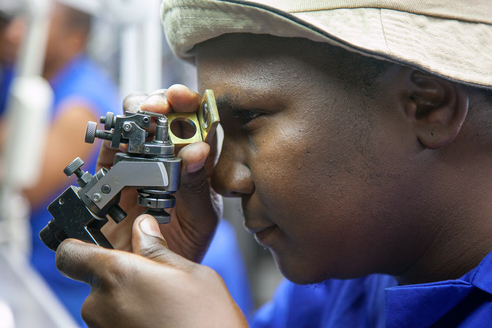 Diamond polishing craftsman using precision optical equipment at Steinmetz Botswana showing skilled manufacturing work