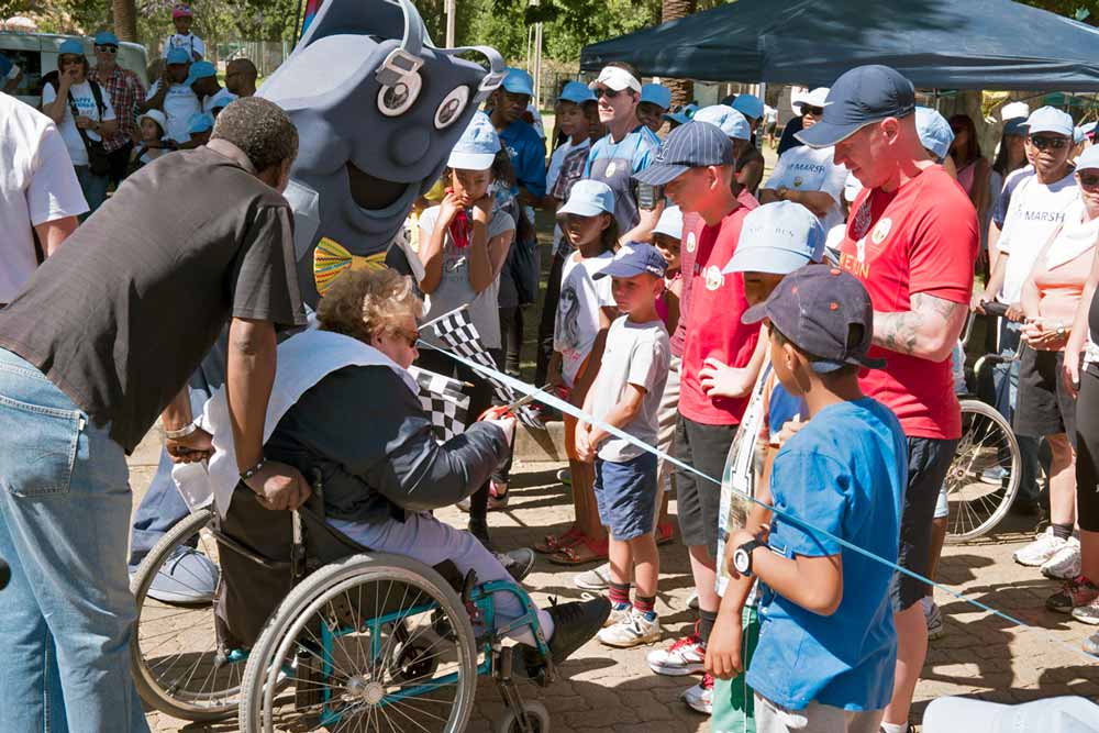 A woman in a wheelchair cutting the ceremonial ribbon to start the Nappy Run at Johannesburg Zoo