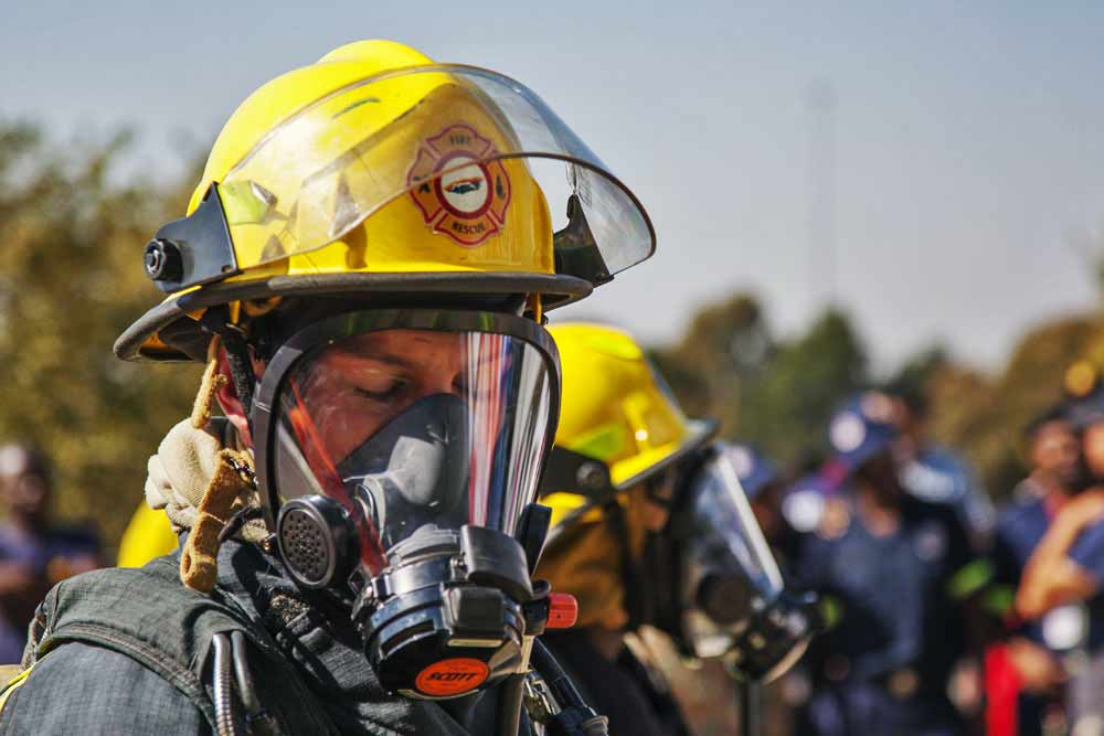 Close-up firefighter in yellow helmet wearing full face breathing apparatus at emergency rescue competition event