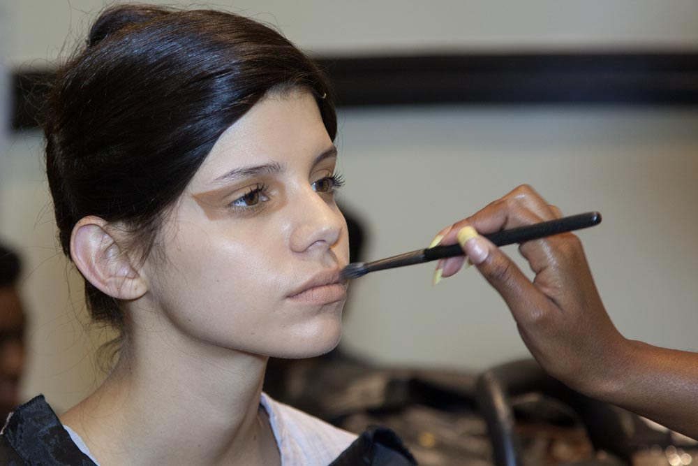 Professional makeup artist applying foundation to fashion model backstage at Johannesburg fashion event
