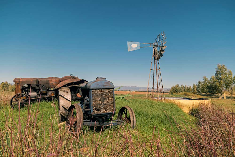 Antique tractors on a rural farm with a windmill in Clarens, Free State